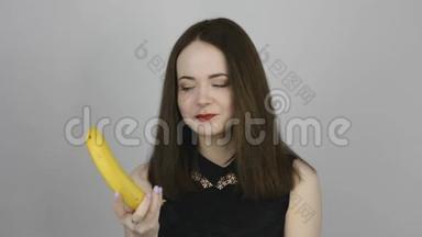 可爱的年轻女人吃着香蕉微笑着